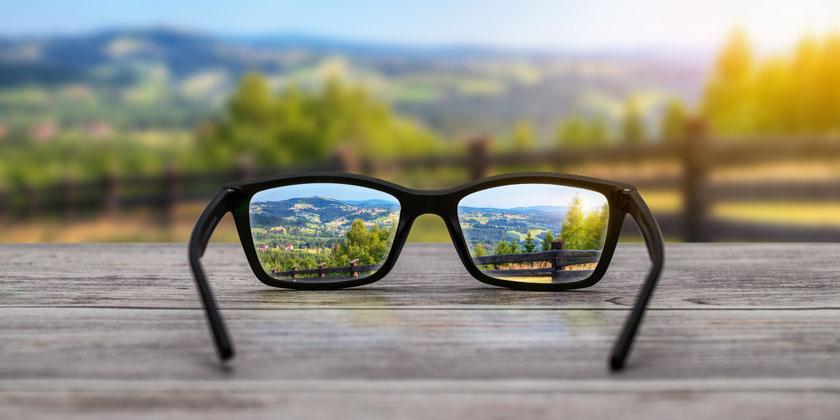 Glasses on a table with a nature scene in their lenses