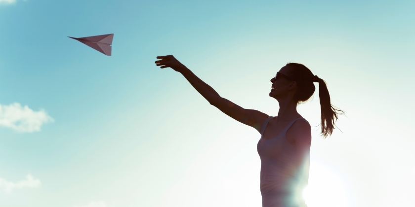 Woman throwing paper airlplane