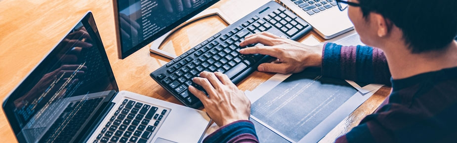 man sitting in front of 3 laptops