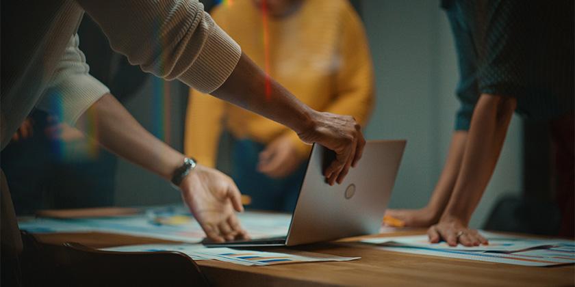 Colleagues at table use laptop, make notes 840x420.jpg