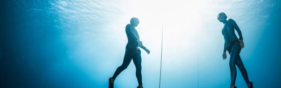 Two divers facing each other in the ocean