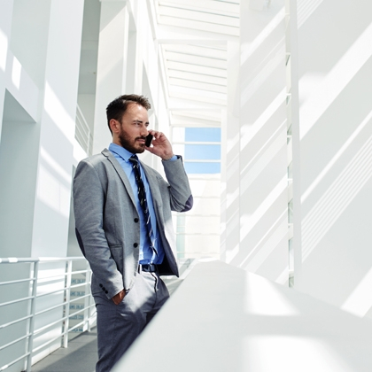 Man on telephone standing outside an office balcony