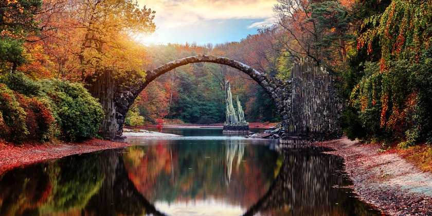 autumnal picture of a bridge going across water