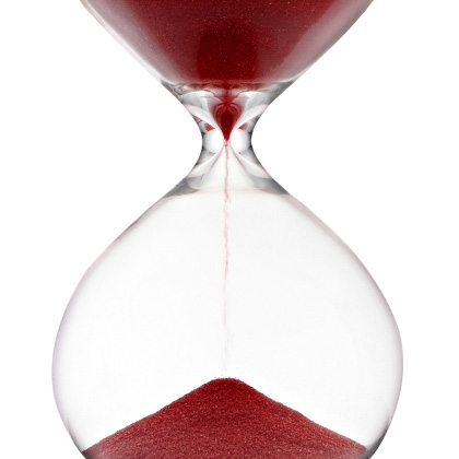 hourglass filled with red sand running down