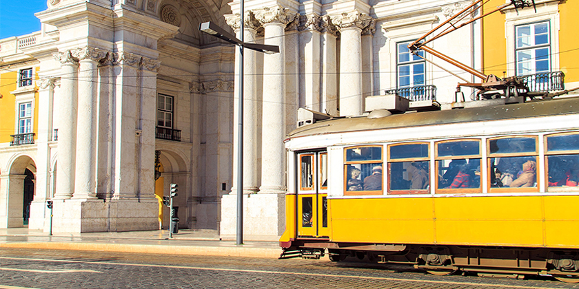 Yellow tram passing a building