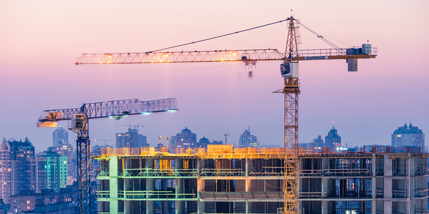 Building site with two cranes and purple sky