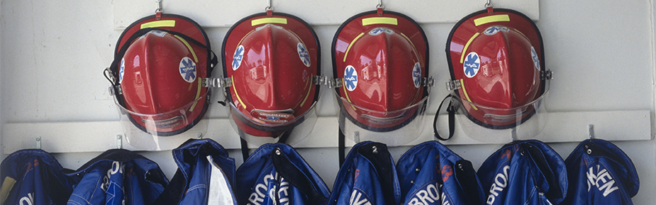 Row of hanging blue fire jackets and red fire helmets