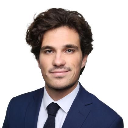 Portrait professionnelle de Victor Bardon portant un costume bleu avec une chemise blanche et une cravate sombre, photographiée sur fond blanc