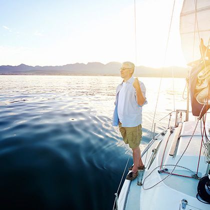 man standing on sailing boat at sunrise