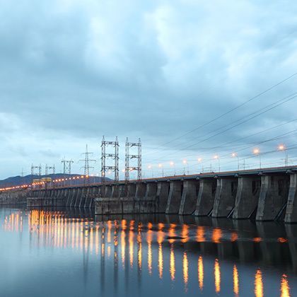 hydroelectric power station at cloudy evening, posts with high-voltage wires