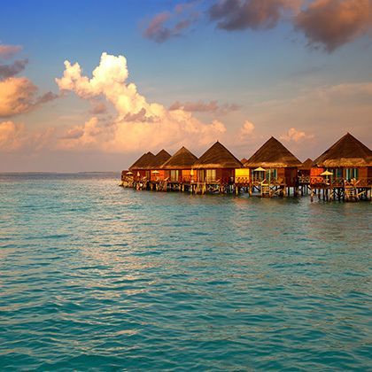 villas standing on piles in water at sunset