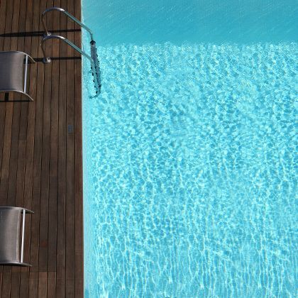 bird's eye view on a blue hotel swimming pool with wooden planks aside