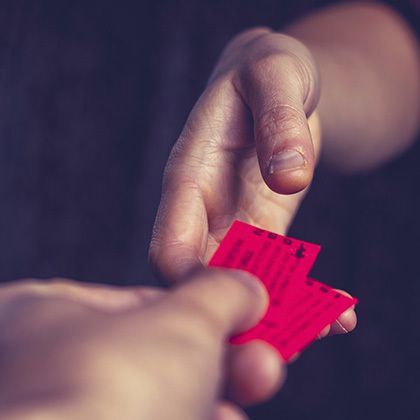 two hands exchanging red tickets