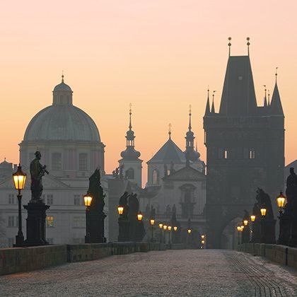 view from charles bridge with illuminated lanterns at dawn in prague, czech republic
