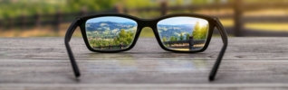 Glasses on a table with a nature scene in their lenses