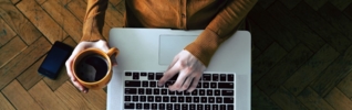 person holding a coffee cup with laptop on knee