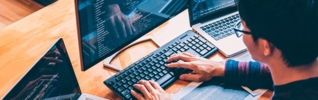 man sitting at desk typing on a keyboard