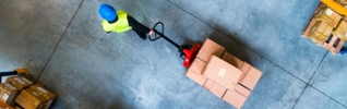 man pulling trolley of boxes in warehouse