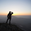 silhouette of a man saluting to the early morning sunrise fro a mountain top