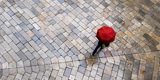 person under a red umbrella standing in the street