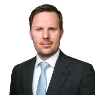 portrait of Georg Gutfleisch, short blong hair. He is wearing a grey suit and a light blue tie..