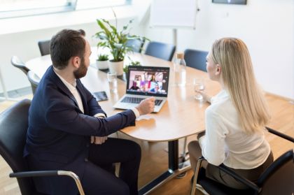 A man and woman sit at a table, collaborating on a laptop, engaged in discussion and sharing ideas.