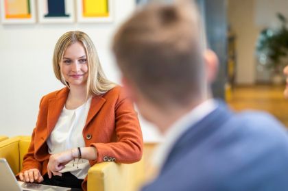 A woman in an office engaged in conversation with another person, both appearing focused and attentive.